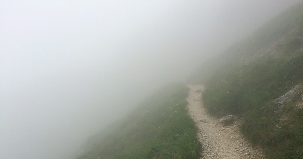 A path in the mountains that shows the way ahead through the fog, accompanied by the psychotherapist Matthias Tschannett, and provides information about his offer in the fields of psychotherapy, coaching and supervision.